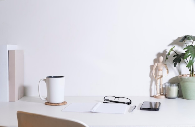 Lieu de travail confortable avec tasse à café téléphone intelligent plante en pot et papeterie sur tableau blanc