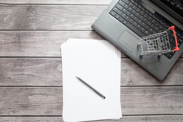 Lieu de travail dans le bureau à domicile avec gadgets papeterie clavier d'ordinateur chariot d'épicerie achats en ligne