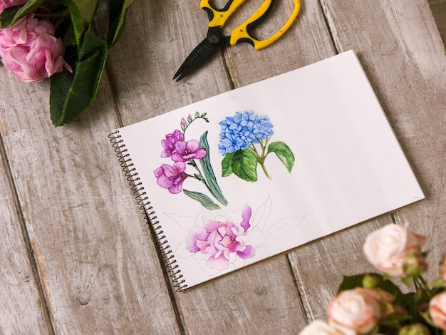 Lieu de travail de décorateur, fleuriste. Croquis de la vue de dessus de fleur. Outils professionnels. Table en bois d'atelier de fleuriste avec décor. Oeuvre décorative à l'aquarelle