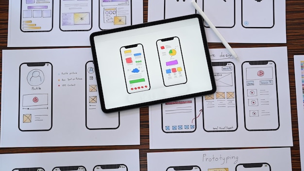Photo lieu de travail de développeur web avec des croquis d'application mobile sur une table en bois mise à plat vue de dessus