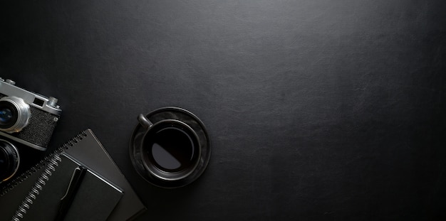 Lieu de travail élégant avec tasse à café et fournitures de bureau sur une table en cuir noir