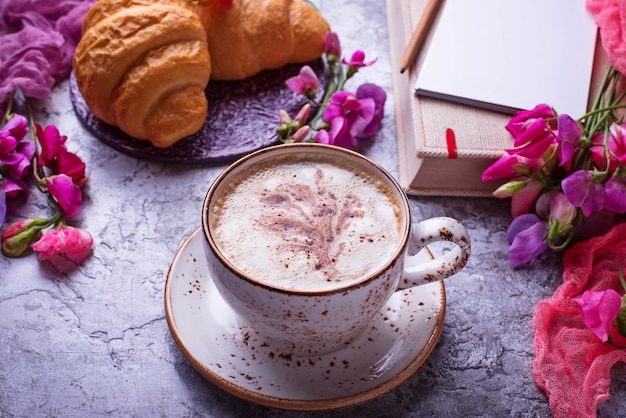 Lieu de travail des filles. Café, croissants, fleurs et cahier. Vue de dessus