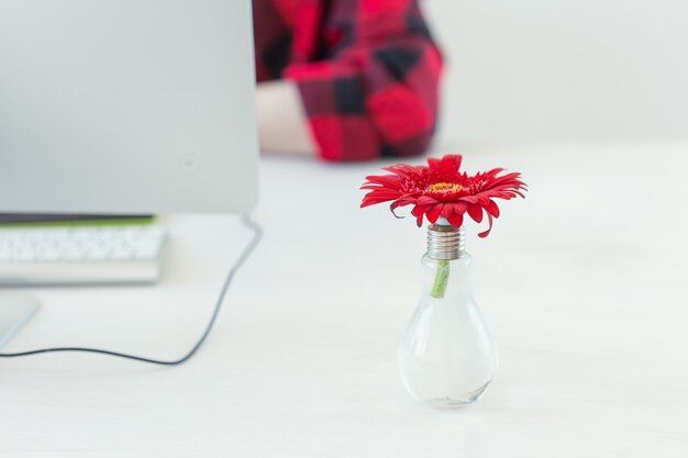 Lieu de travail avec fleur de gerbera et ordinateur. Bureau à domicile minimaliste avec concepteur en arrière-plan