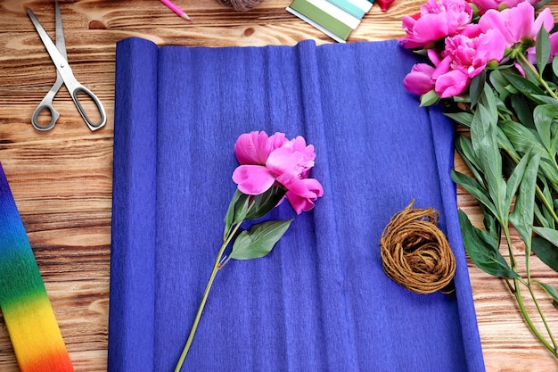 Lieu de travail de fleuriste avec pivoines fraîches et papier d'emballage sur table en bois