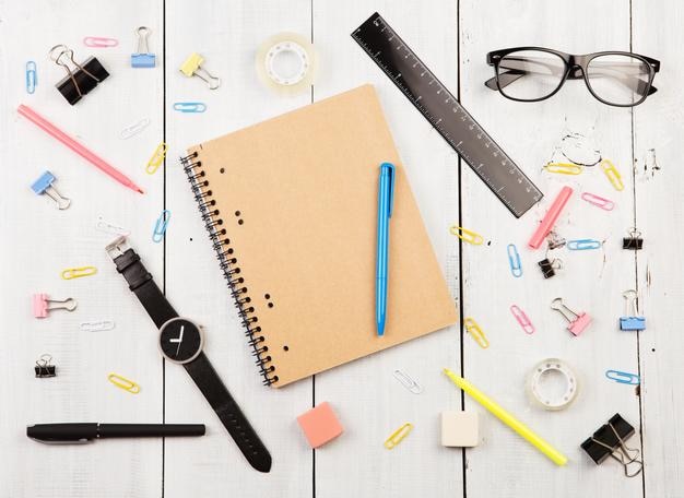 Lieu de travail avec des lunettes de bloc-notes, des stylos de montre et d'autres fournitures de bureau sur une table en bois blanc