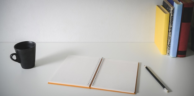 Lieu de travail minimal avec un cahier vierge ouvert, des fournitures de bureau, une tasse de café et un espace de copie