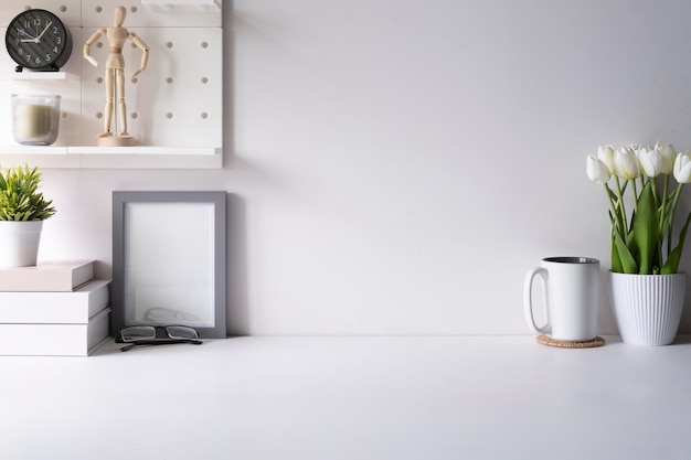 Lieu de travail moderne et lumineux avec pot de fleur tasse à café cadre photo et livres sur tableau blanc Copiez l'espace pour votre texte