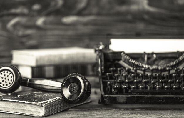 Photo lieu de travail vintage avec machine à écrire, téléphone et livres sur table