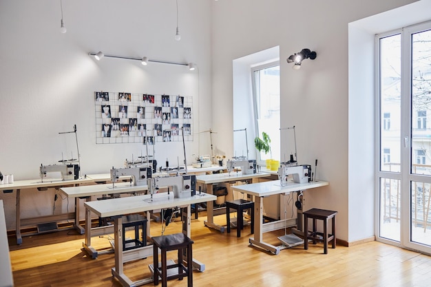 Lieux de travail avec machines à coudre et photos de modèles de robes élégantes sur le mur en atelier