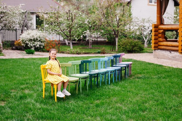 Une ligne de chaises en bois sur la pelouse dans l'arrière-cour pour des vacances en famille dans un jardin de printemps fleuri