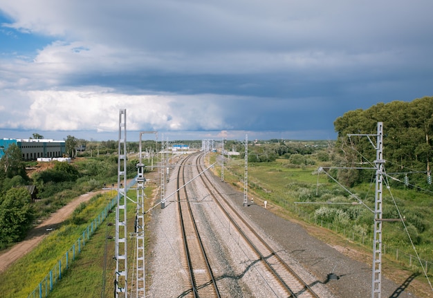 Ligne de chemin de fer s'étendant dans l'horizon sur un fond de ciel nuageux