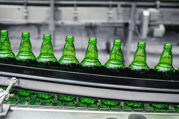 Photo ligne de convoyage automatisée dans une brasserie. des rangées de bouteilles en verre vert sur le gros plan du convoyeur.