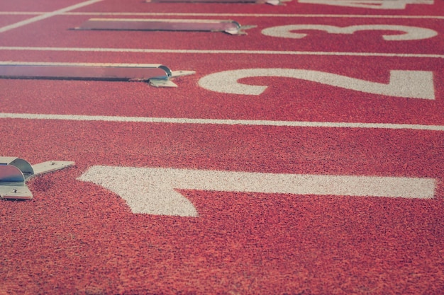 Ligne de départ. Piste de course rouge avec numéros de voie. Contexte sportif.