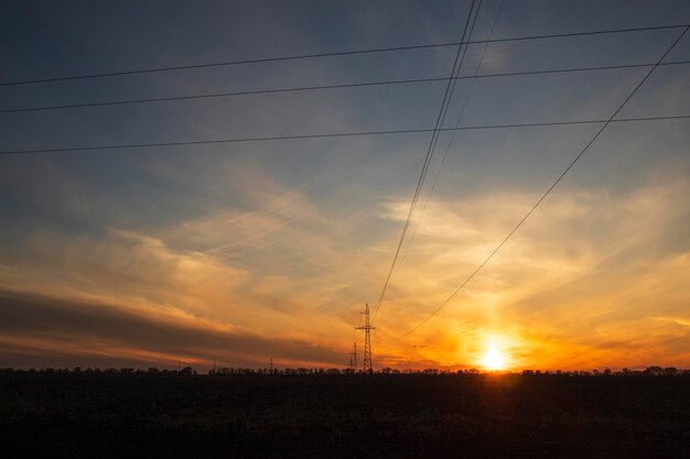 Ligne électrique sur le fond d'un paysage avec un coucher de soleil poteaux électriques soir