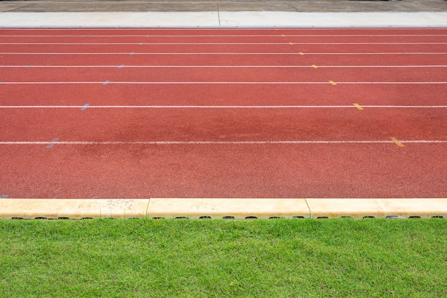 Lignes blanches du stade et texture des pistes de course en caoutchouc rouge