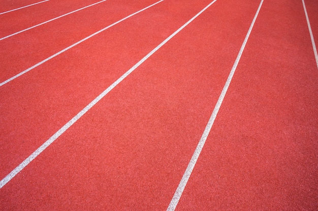 Lignes blanches du stade et texture des pistes de course en caoutchouc rouge