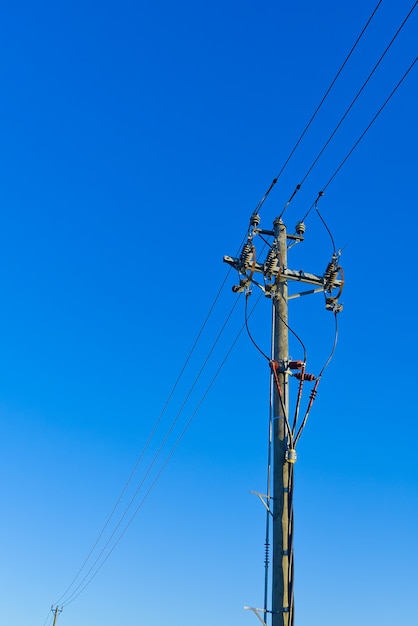 Lignes électriques du ciel et connexions sur un poteau en bois. Poteau électrique en bois contre le ciel bleu