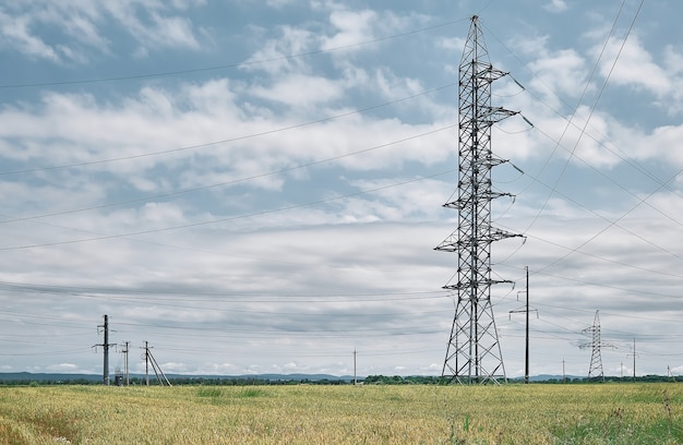 Lignes électriques haute tension, paysage sur un champ vert à midi, belle journée ensoleillée, ciel bleu avec des nuages. Approvisionnement énergétique pour la vie urbaine