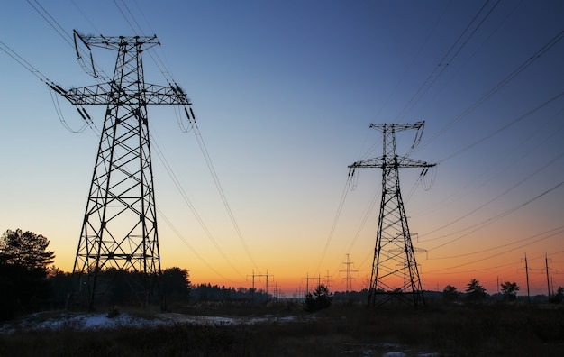 Lignes électriques à haute tension pendant le lever du soleil enflammé