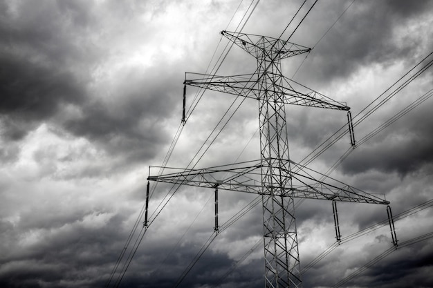 Lignes électriques de transport d'électricité et nuages sombres sur le ciel