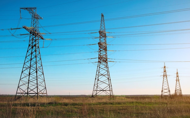 Lignes à haute tension et pylônes électriques dans un paysage agricole plat et vert par une journée ensoleillée avec des nuages dans le ciel bleu Nuageux et pluvieux Le blé pousse