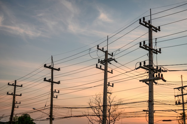 Lignes rurales de pôle électrique avec réseau de fils au coucher du soleil