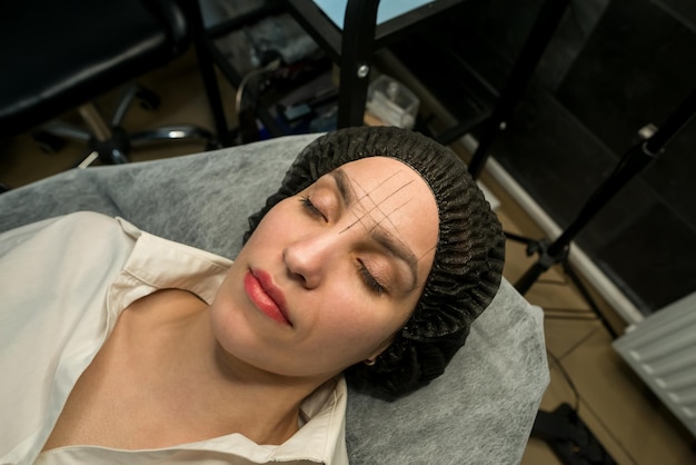 Des lignes sont dessinées sur les sourcils de la fille pour créer la forme parfaite des sourcils