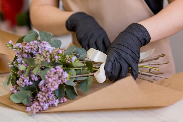 Photo lilas entre les mains d'une fleuriste qui crée un bouquet dans un magasin de fleurs