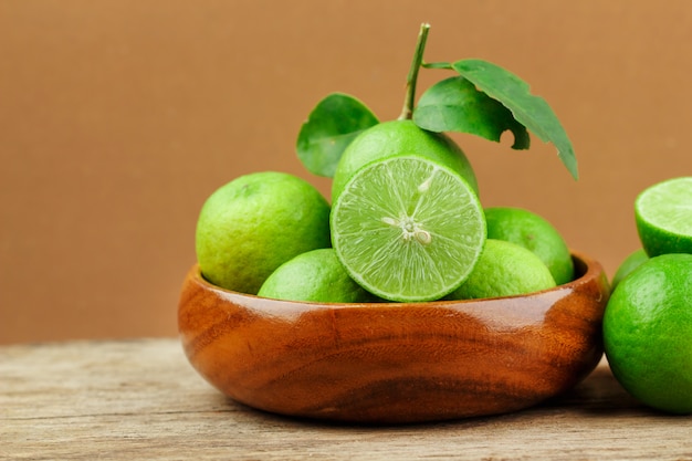 Limes fraîches dans un bol en bois sur fond en bois