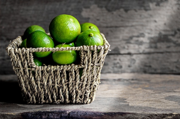 Limes fraîches dans le panier sur un fond en bois