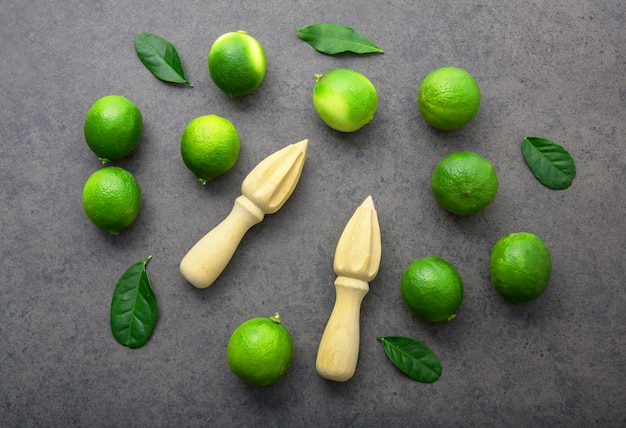 Limes fraîches et presse-agrumes en bois sur fond blanc. Vue de dessus