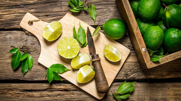 Limes tranchées sur une planche avec un couteau et une boîte pleine.