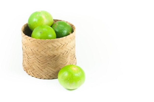 Limes vertes fraîches dans le panier de bambou isolé sur fond blanc