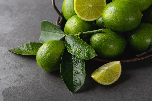 Limes vertes fraîches avec des feuilles sur un plateau