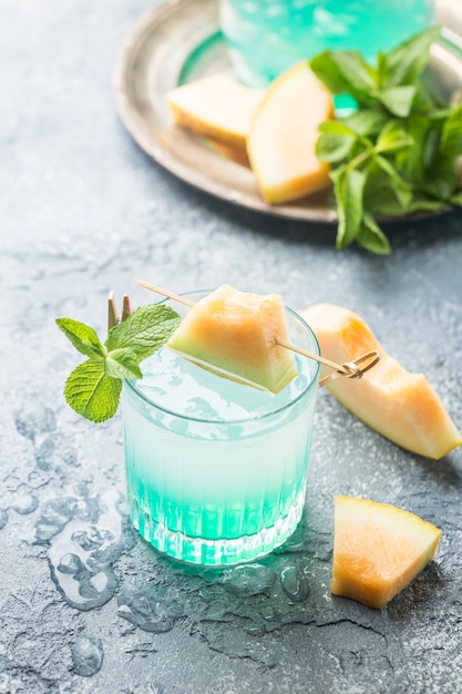 Limonade au melon avec de la glace et de la menthe dans un verre sur la table grise boisson rafraîchissante d'été