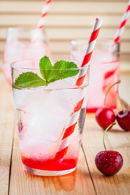 Limonade aux cerises avec de la glace dans des verres sur une table en bois table en bois