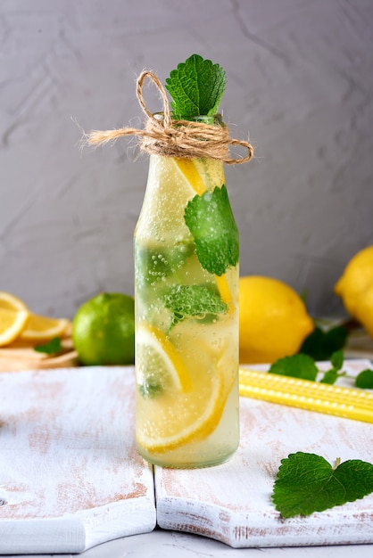 limonade aux citrons, feuilles de menthe, citron vert dans une bouteille en verre