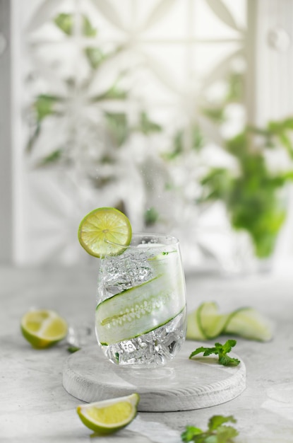 Limonade cocktail de concombre au citron vert contre haie blanche dans un jardin verdoyant