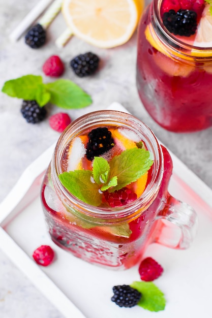 Limonade à la framboise et mûre au citron, menthe dans un bocal à conserves.