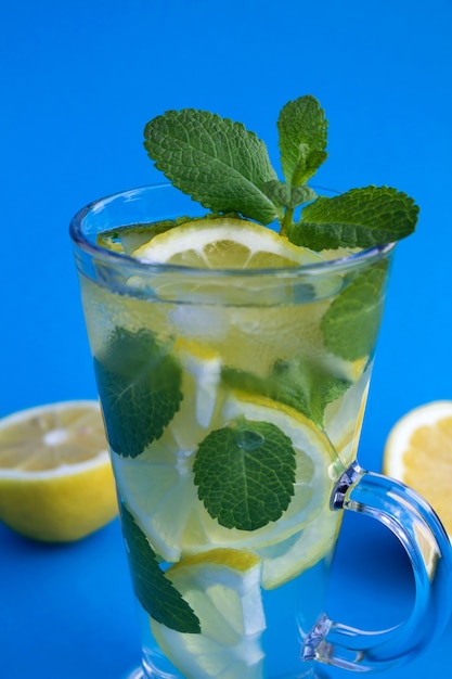 Limonade froide au citron et à la menthe dans le verre sur fond bleu.Gros plan.