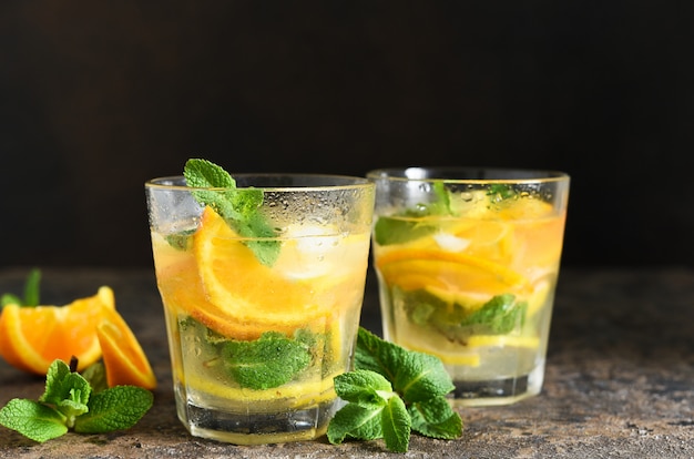 Limonade froide au citron, orange et menthe sur une table en béton.