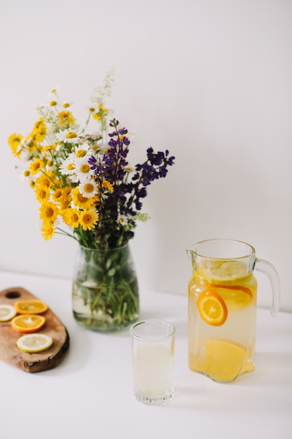 Limonade maison à l'orange et au citron et un bouquet de fleurs naturelles sauvages sur tableau blanc