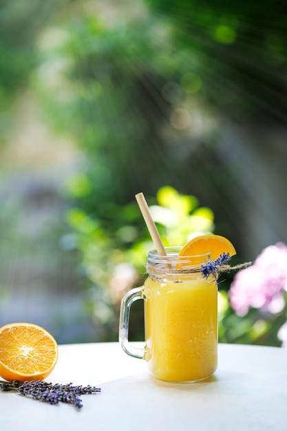 Limonade orange dans une tasse sur la table inondée de soleil