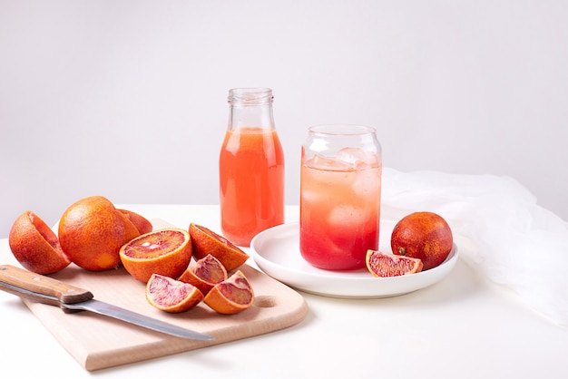 Limonade à l'orange sanguine dans un verre avec des gouttes et des glaçons, eau fonctionnelle, boisson d'été sur fond blanc