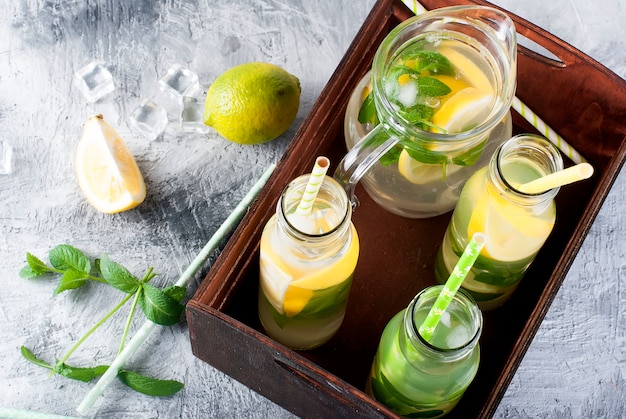 Limonade en pichet en verre et bouteilles de glace et menthe