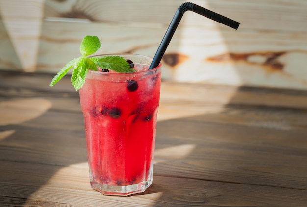 Limonade rafraîchissante rouge avec des baies et de la glace sur une table en bois. Boisson d'été.