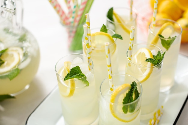 Limonade traditionnelle avec une tranche de citron frais et de menthe avec de la paille de papier dans le verre.