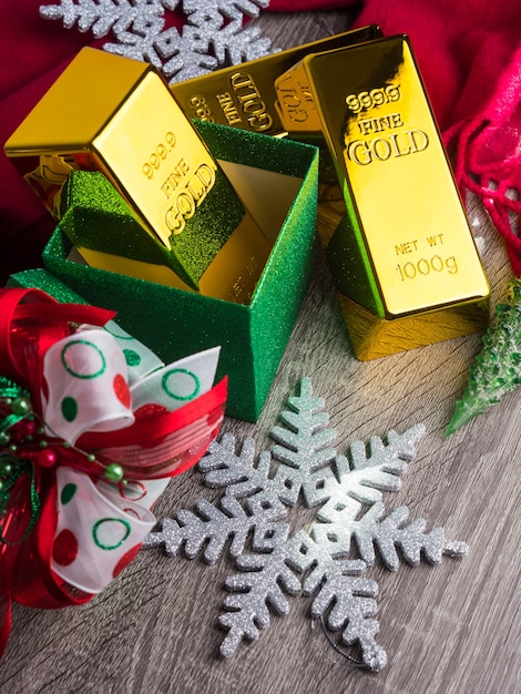 Lingots d'or comme cadeau de Noël sur table en bois avec des ornements.