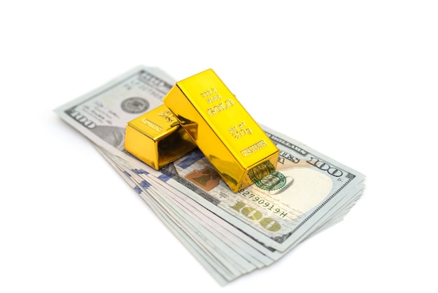 Lingots d'or sur une pile de billets en dollars américains isolés.