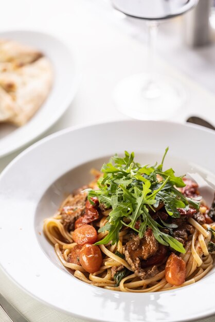 Linguine aux tomates avec viande et roquette servi dans une assiette fantaisie